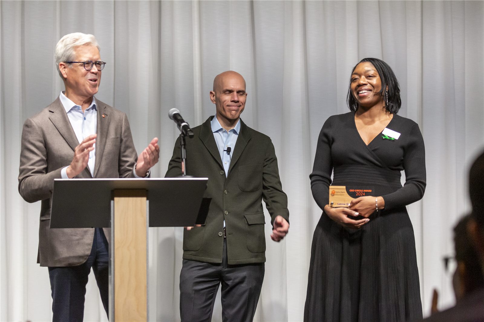 Three leaders presenting on stage at a corporate event