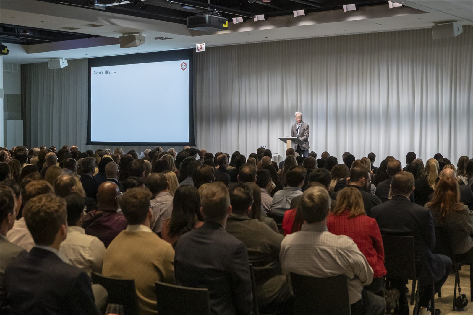 Wide view of a keynote speaker addressing a full conference room