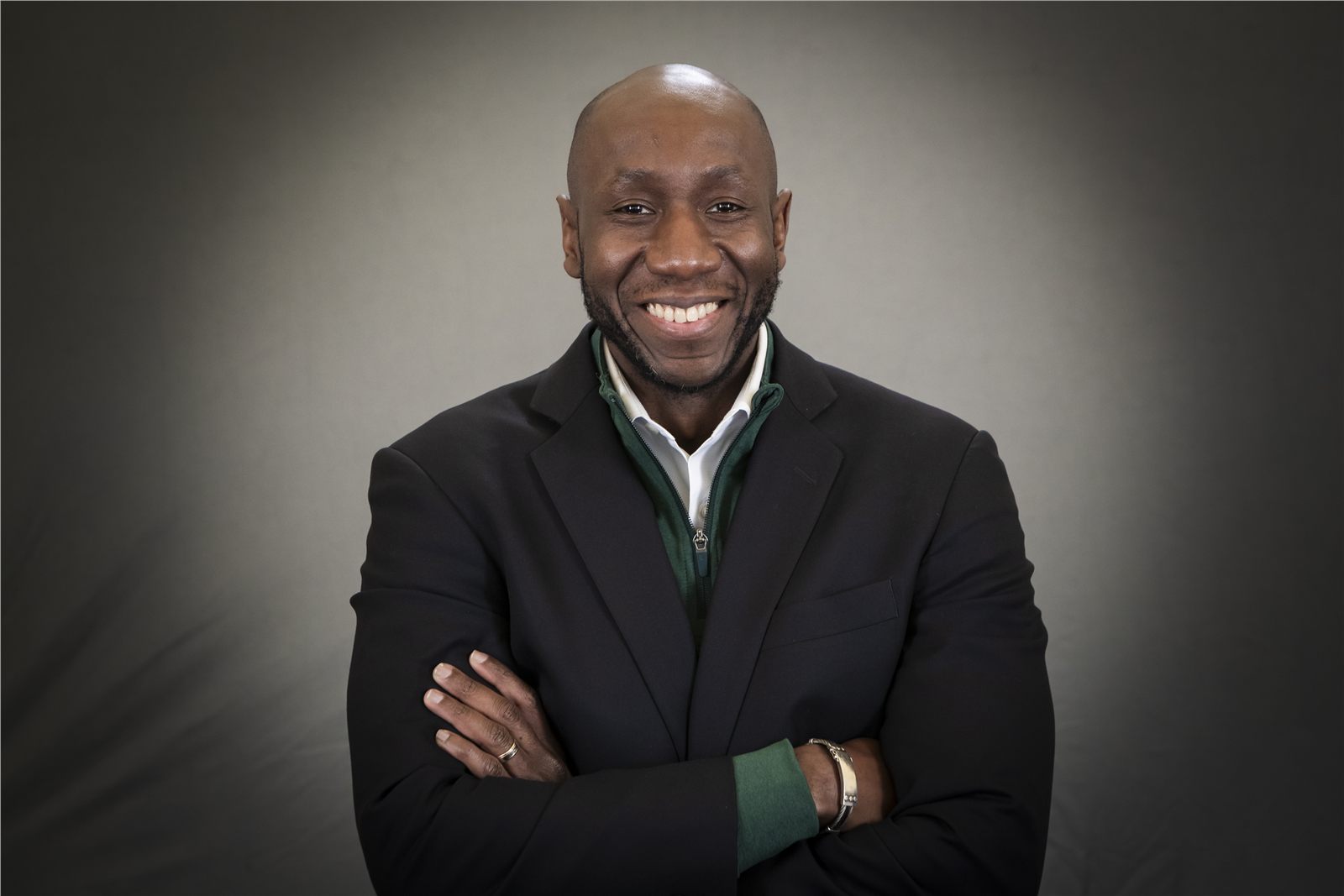 Corporate headshot of a smiling man with arms crossed