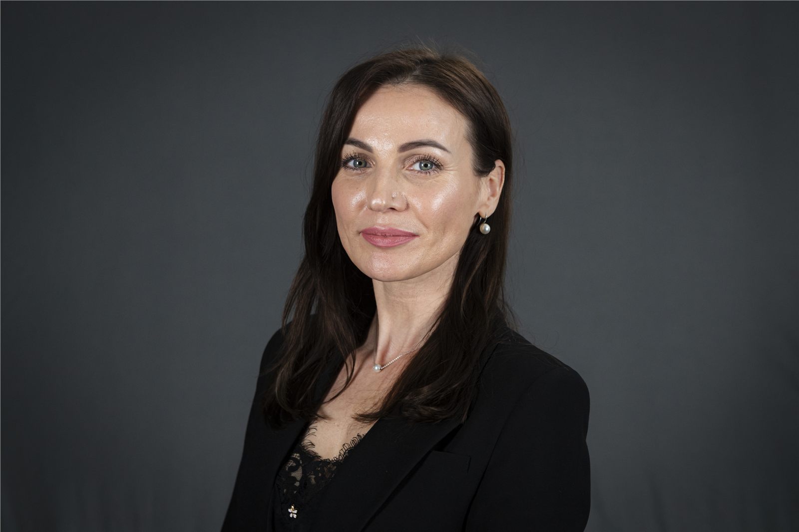 Professional executive headshot of a woman against a dark neutral background