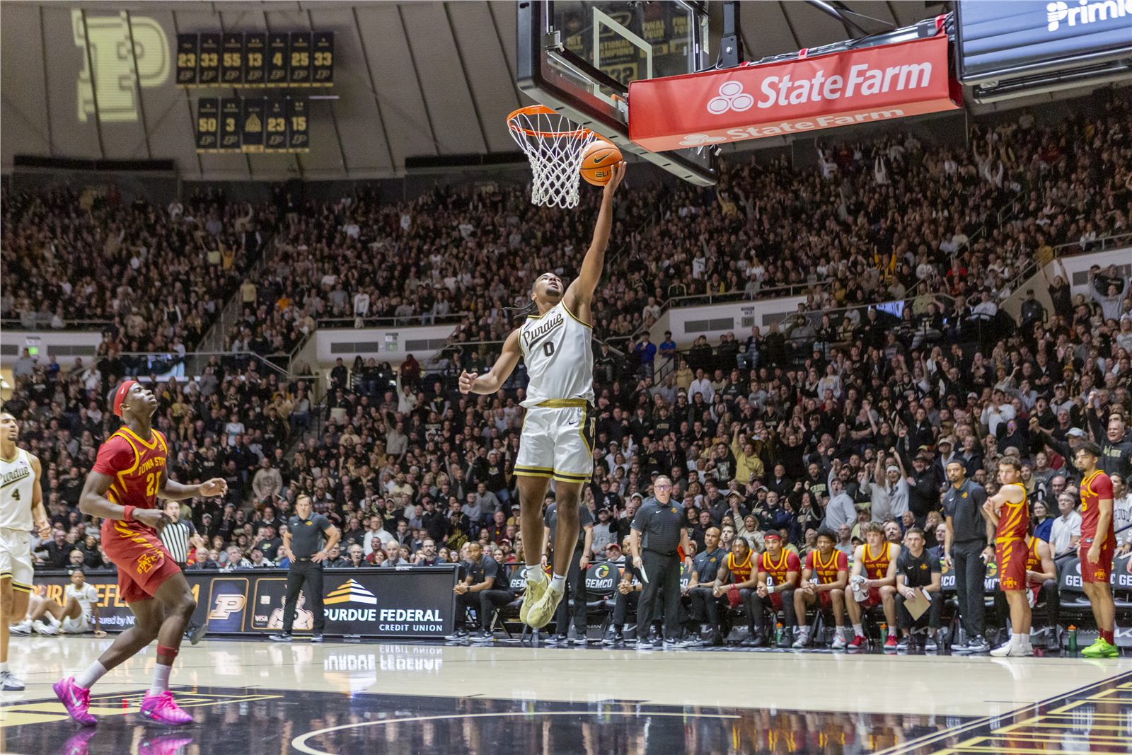 College basketball player completing a dunk before a full arena